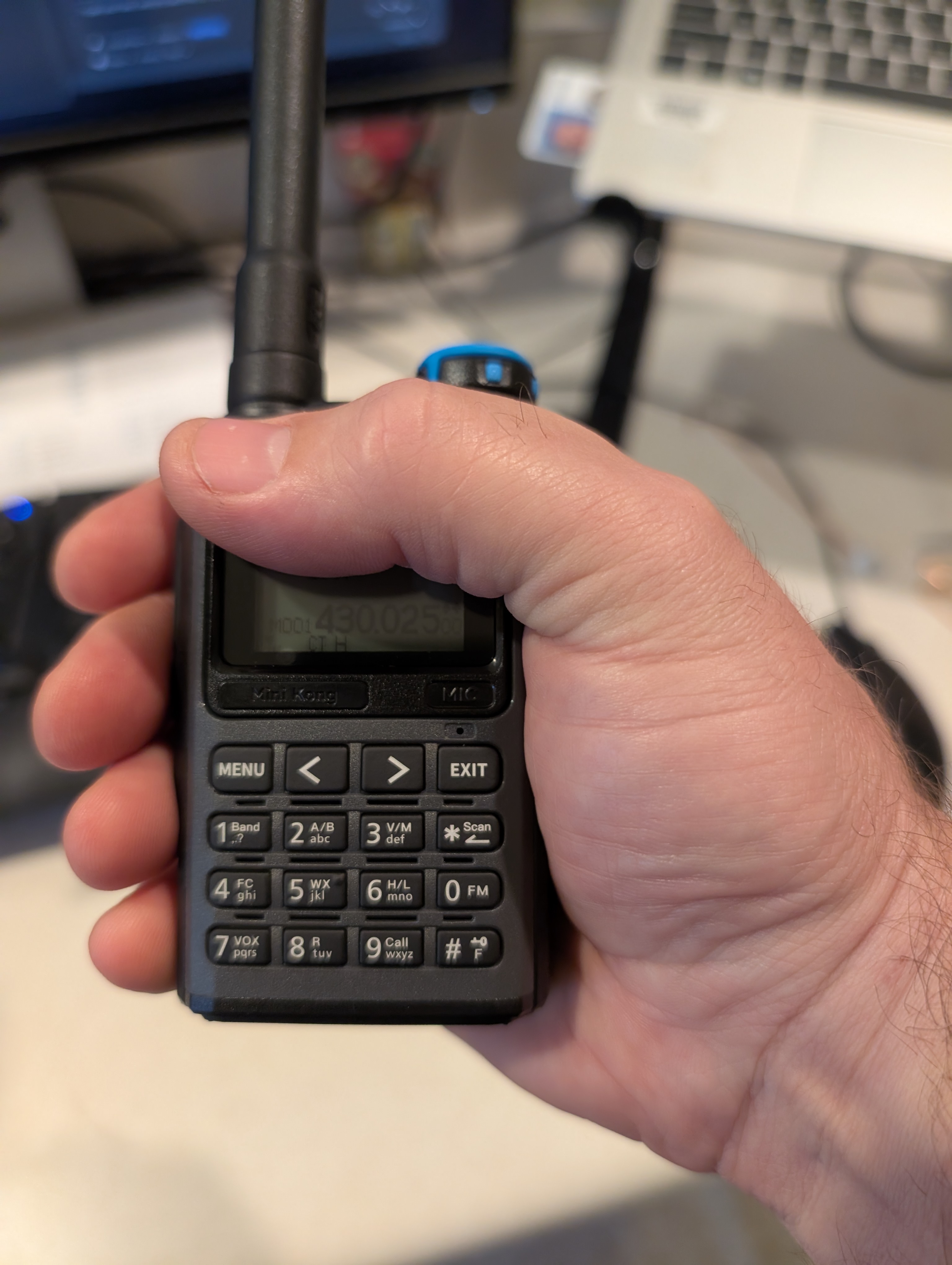 A Quansheng UV-K1 radio in our reviwers hand. Their thumb rests exactly at the edge of the radio, showing both that the radio is wider than the UV5R mini and that it is a pretty good compact fit for most users.