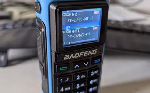 A Baofeng UV-7B showing dual channel mode while sitting on a desk. It has a blue surround on the frame.