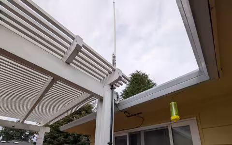 An Ed Fong DBJ-1 antenna mounted to a backyard porch pergola.
